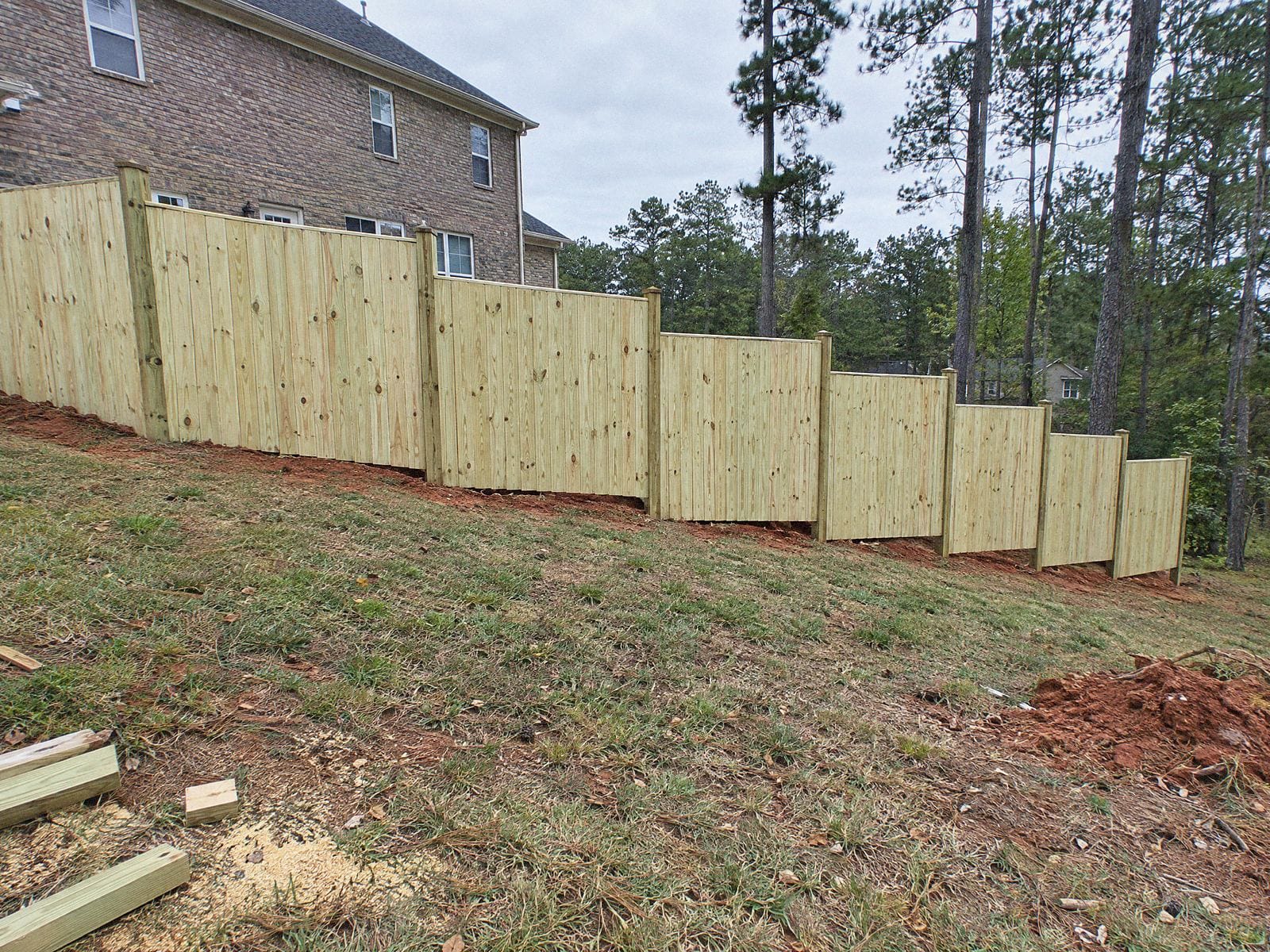 Wood privacy fence stepping down a sloped backyard in level sections